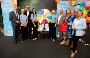 Gruppenfoto bei der Inform 2025 im Burgenland, vor einem Glücksrad, umgeben von bunten Luftballons.