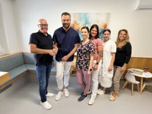Team von Medizinfachleuten freundlicher Empfang in moderner Praxis, Händeschütteln und Lächeln in einladendem Warteraum.