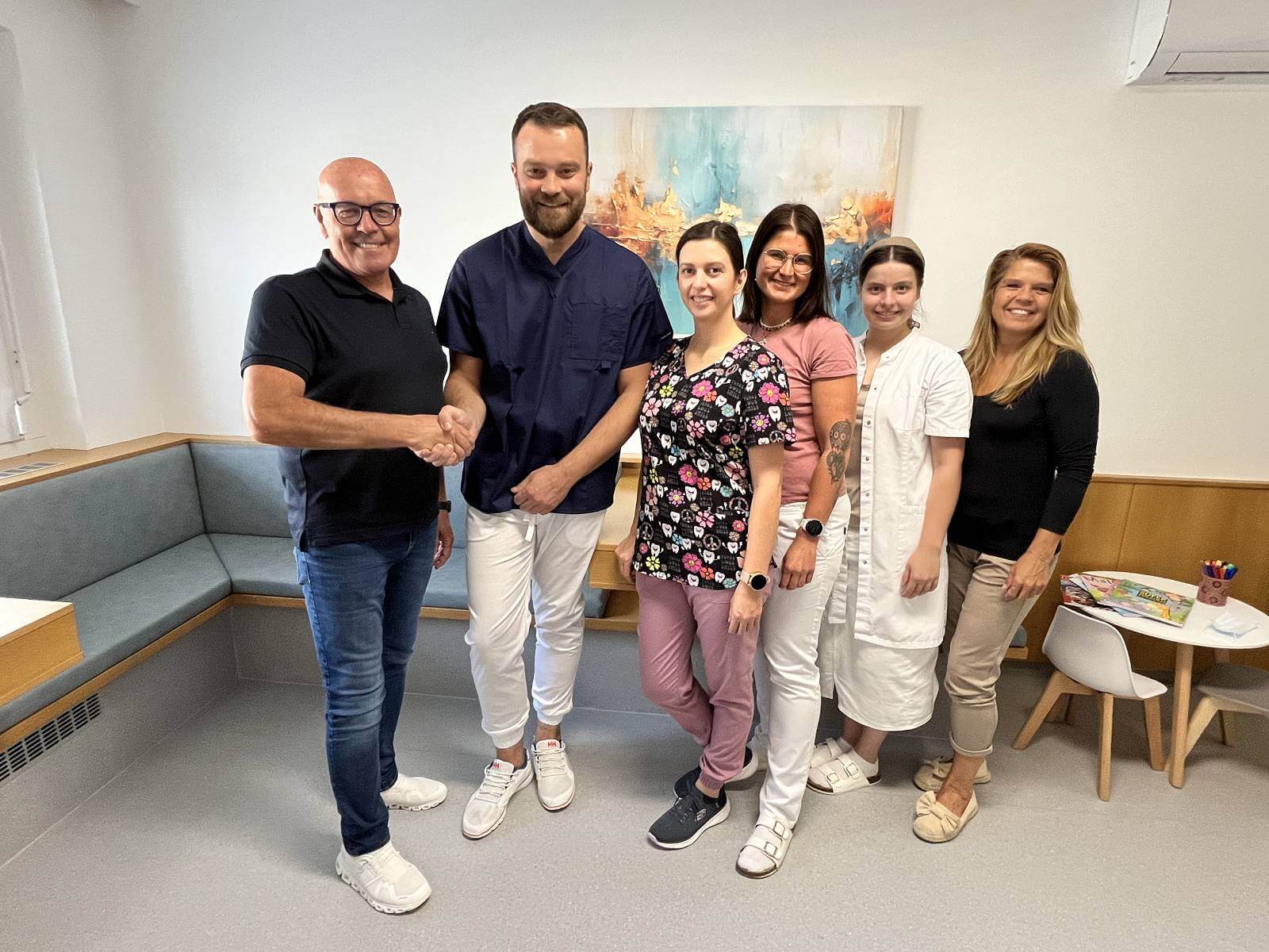 Team von Medizinfachleuten freundlicher Empfang in moderner Praxis, Händeschütteln und Lächeln in einladendem Warteraum.