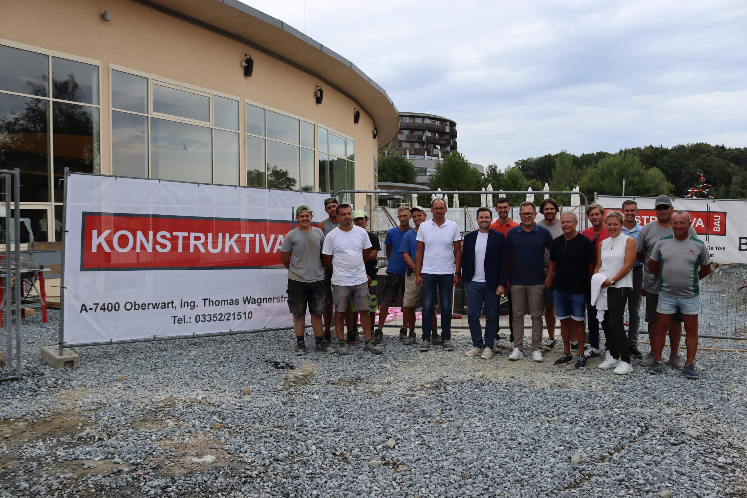 Gruppe von Bauarbeitern vor einem Gebäude mit Konstruktiva-Bau-Banner bei einem Bauprojekt in Oberwart.