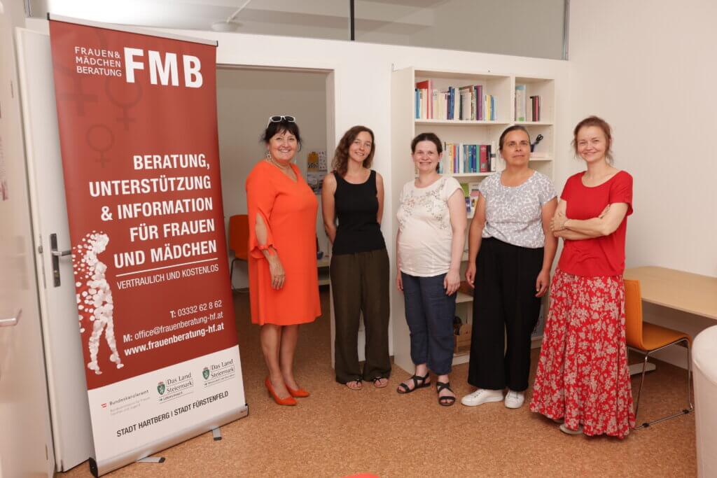 Gruppenfoto im Büro der Frauen- und Mädchenberatung mit Infoposter zu Unterstützung und Beratung.
