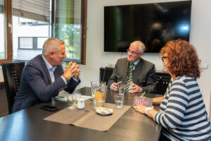 Geschäftstreffen im Büro mit drei Personen am Tisch, Vertiefung in intensive Diskussion.