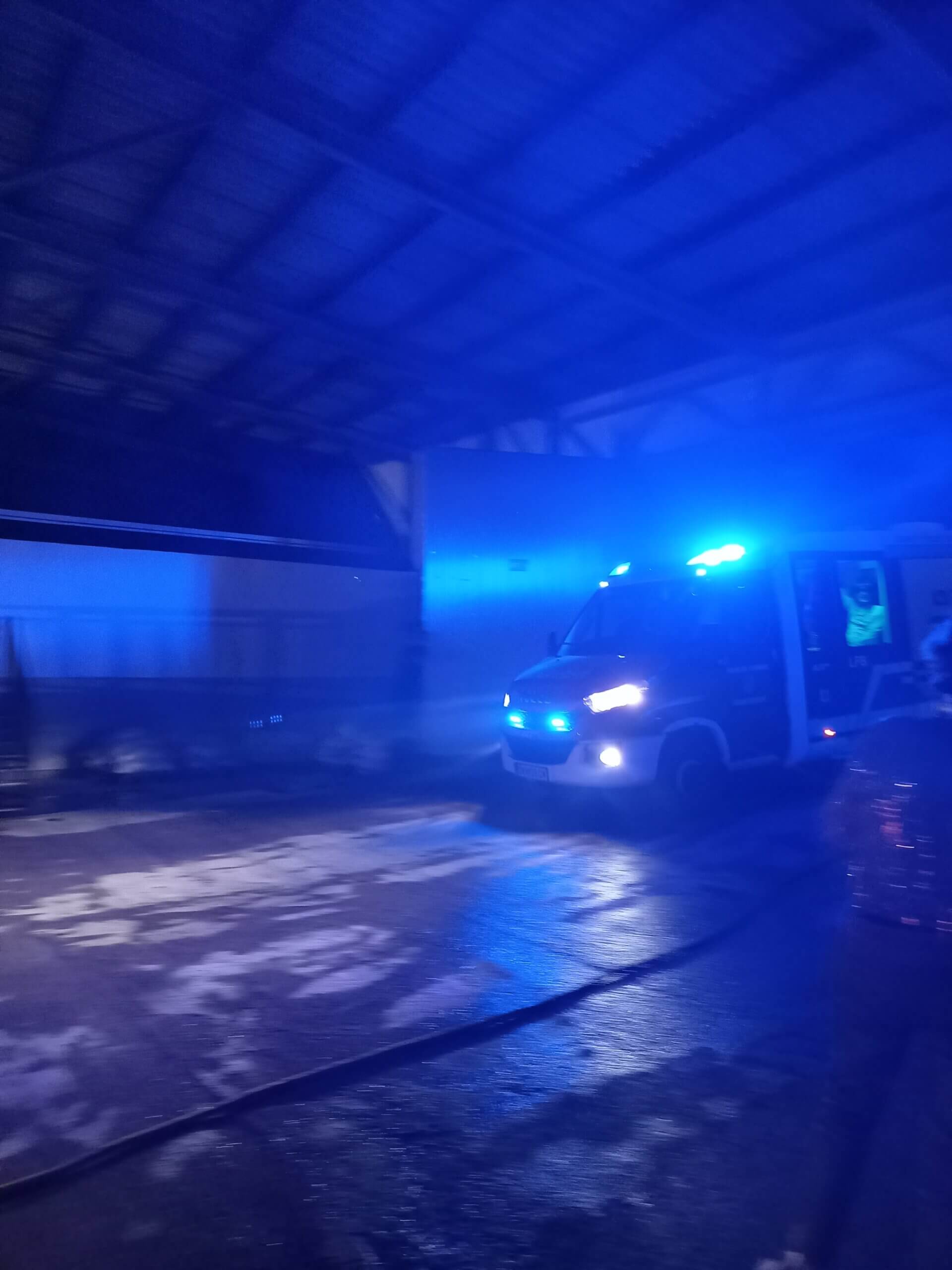 Krankenwagen mit Blaulicht bei Nacht in einem überdachten Bereich für schnelle Notfalleinsätze.