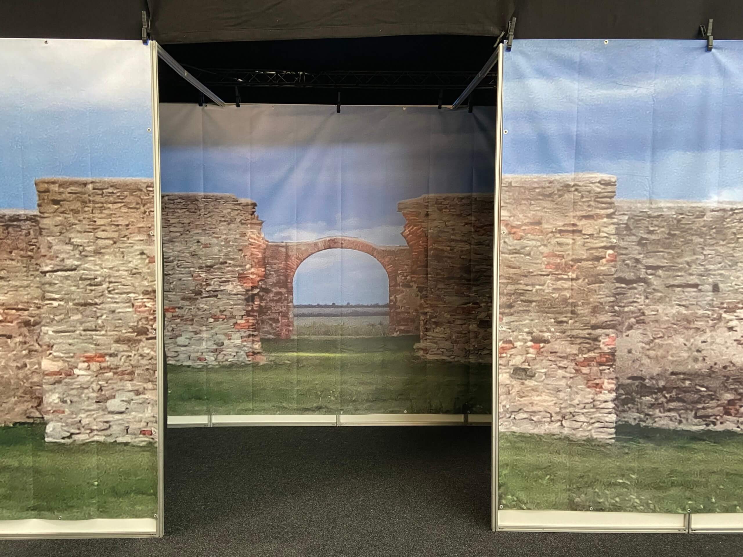 Wandbild mit antiken Steinmauern und Torbogen, suggestiv für historische Architektur in Innenraumausstellung.