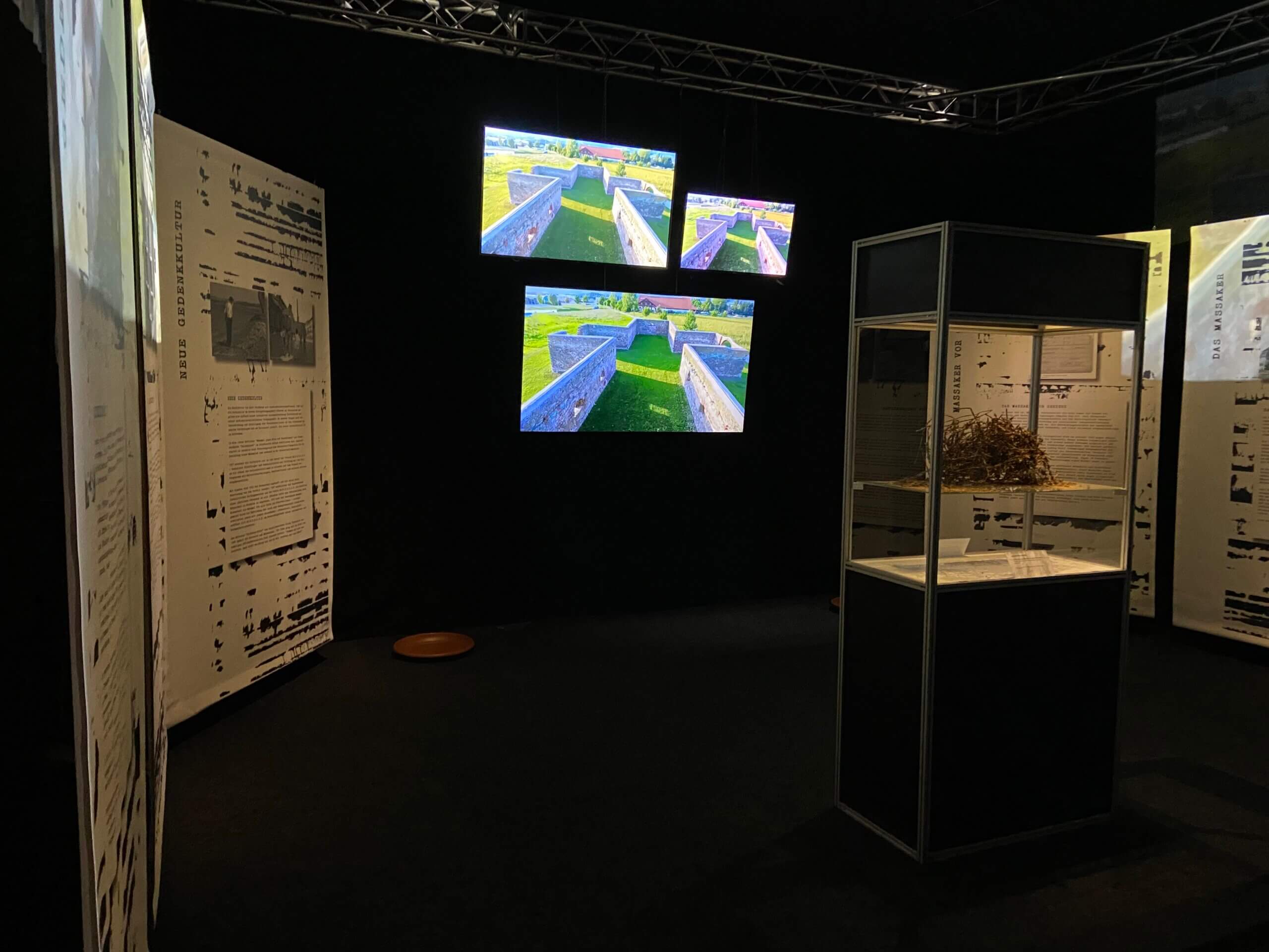 Ausstellungsraum mit historischen Tafeln und Videobildschirmen über archäologische Stätten. Modernes Museumserlebnis.