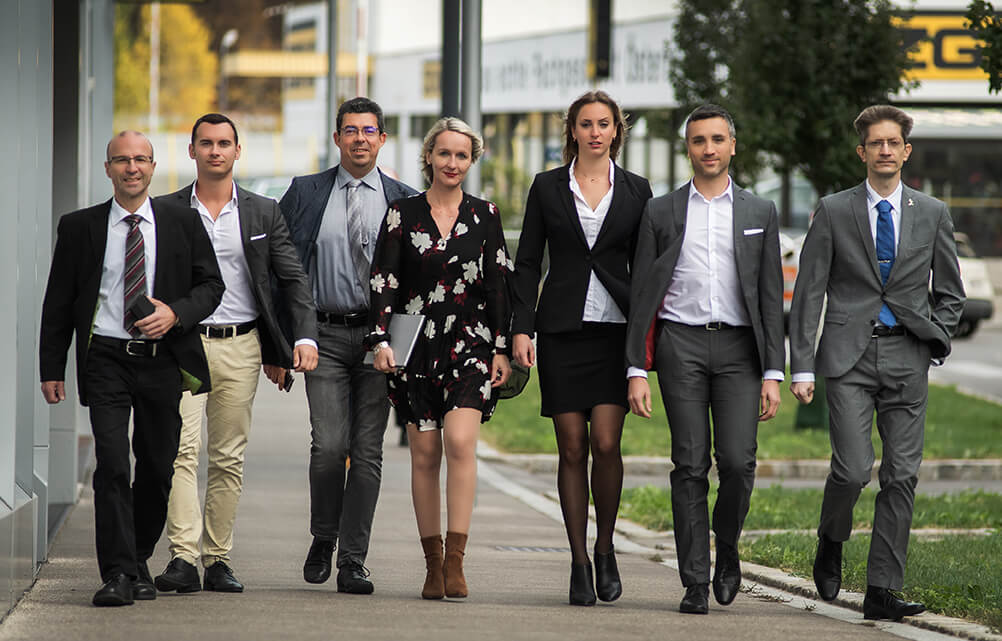 Gruppe von Geschäftsleuten in formeller Kleidung, die gemeinsam im Freien geht.