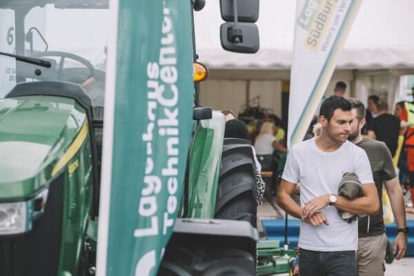 Mann neben grünem Traktor auf Messe, Lagerhaus TechnikCenter-Logo sichtbar.