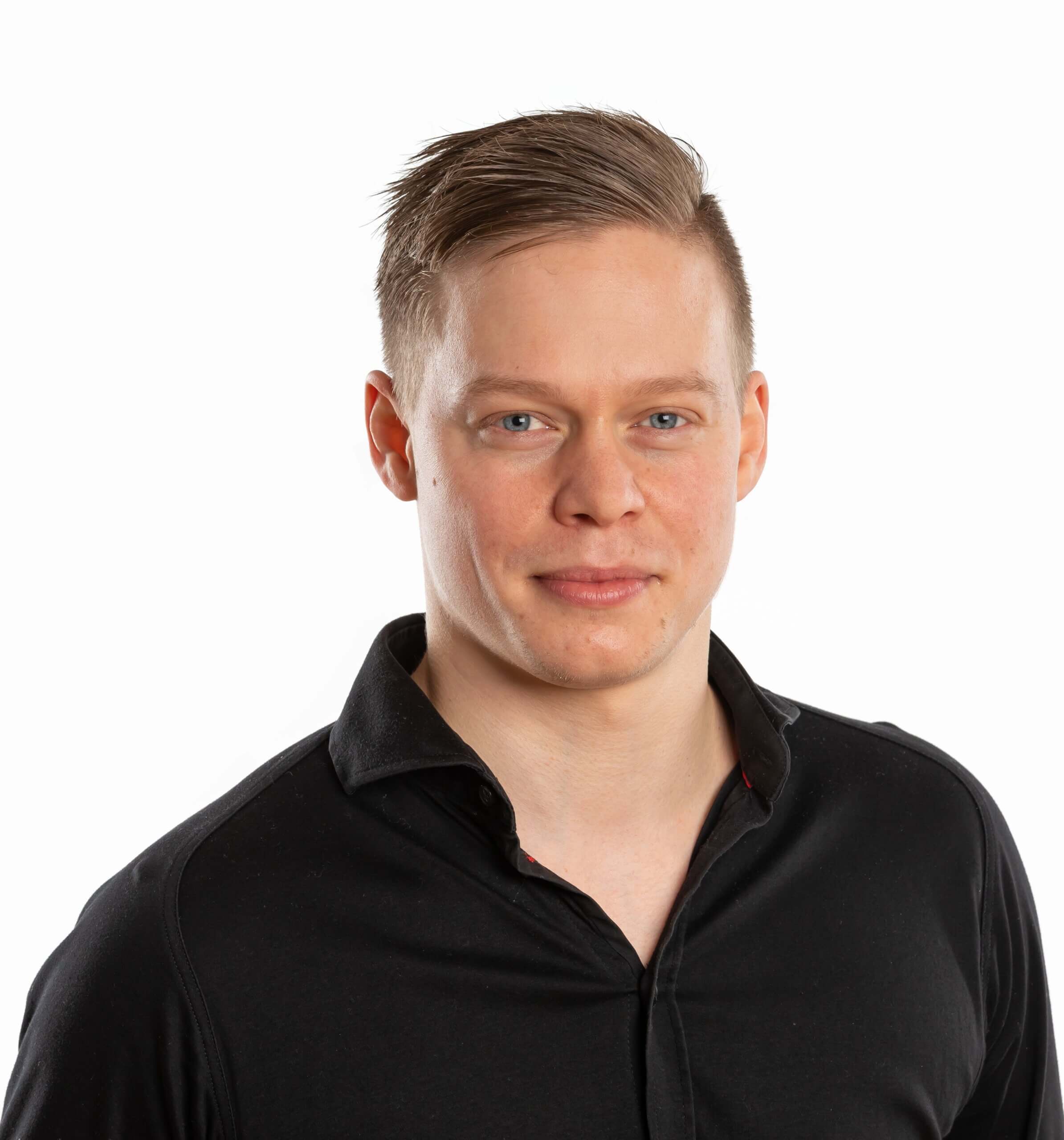 Ein Mann in schwarzem Hemd vor weißem Hintergrund lächelt leicht in die Kamera.