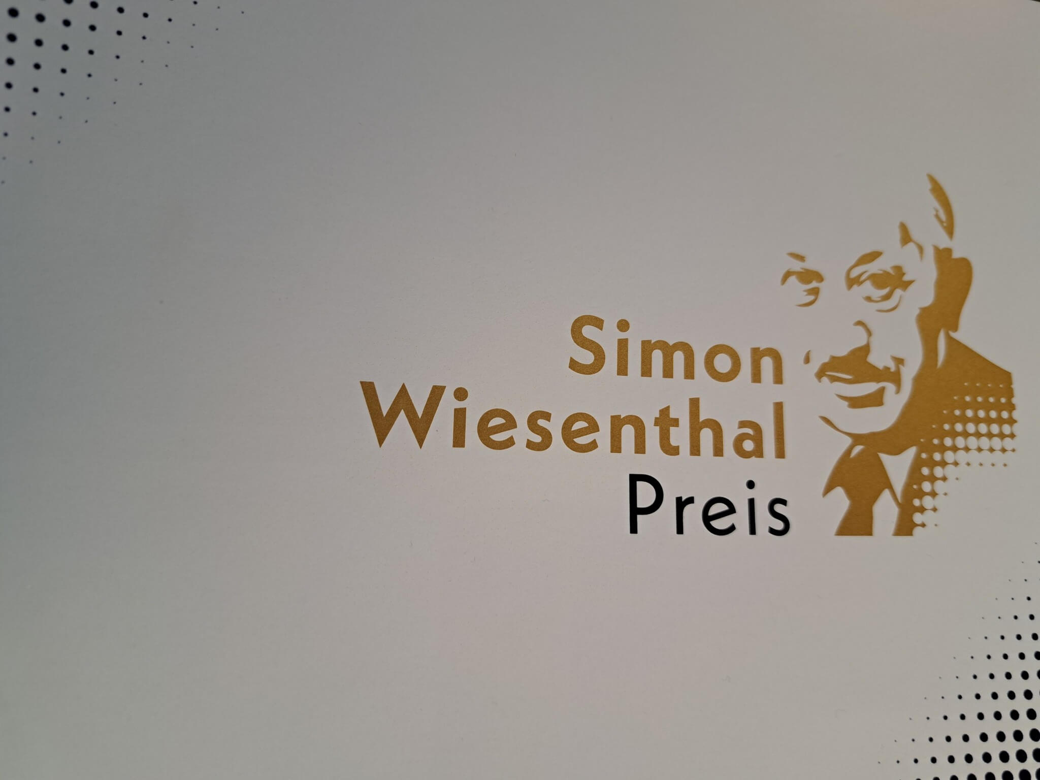 Logo des Simon-Wiesenthal-Preises mit Porträt, goldene Schrift auf weißem Hintergrund.