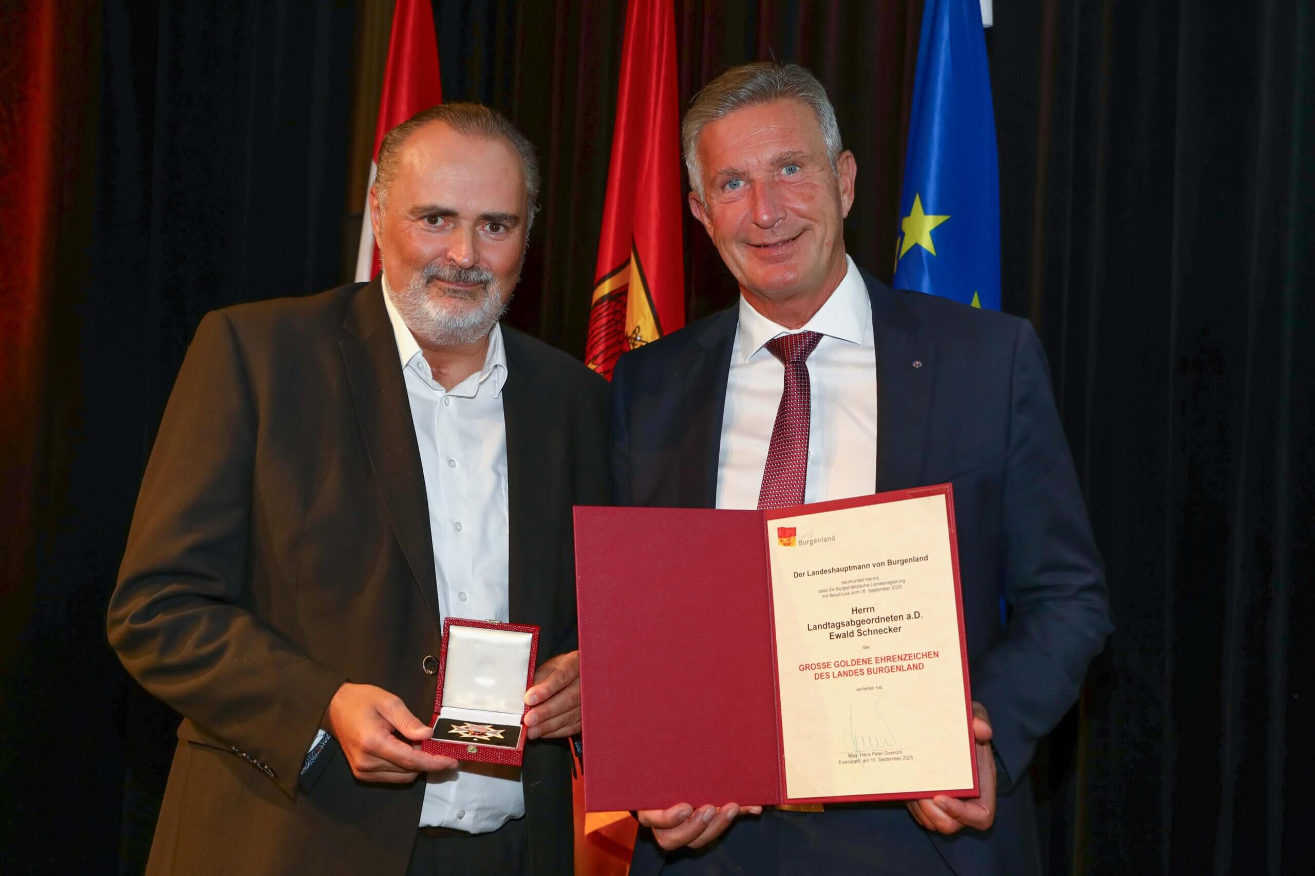 Zwei Männer bei einer Ehrungszeremonie mit Urkunde und Medaille in Burgenland, Österreich.