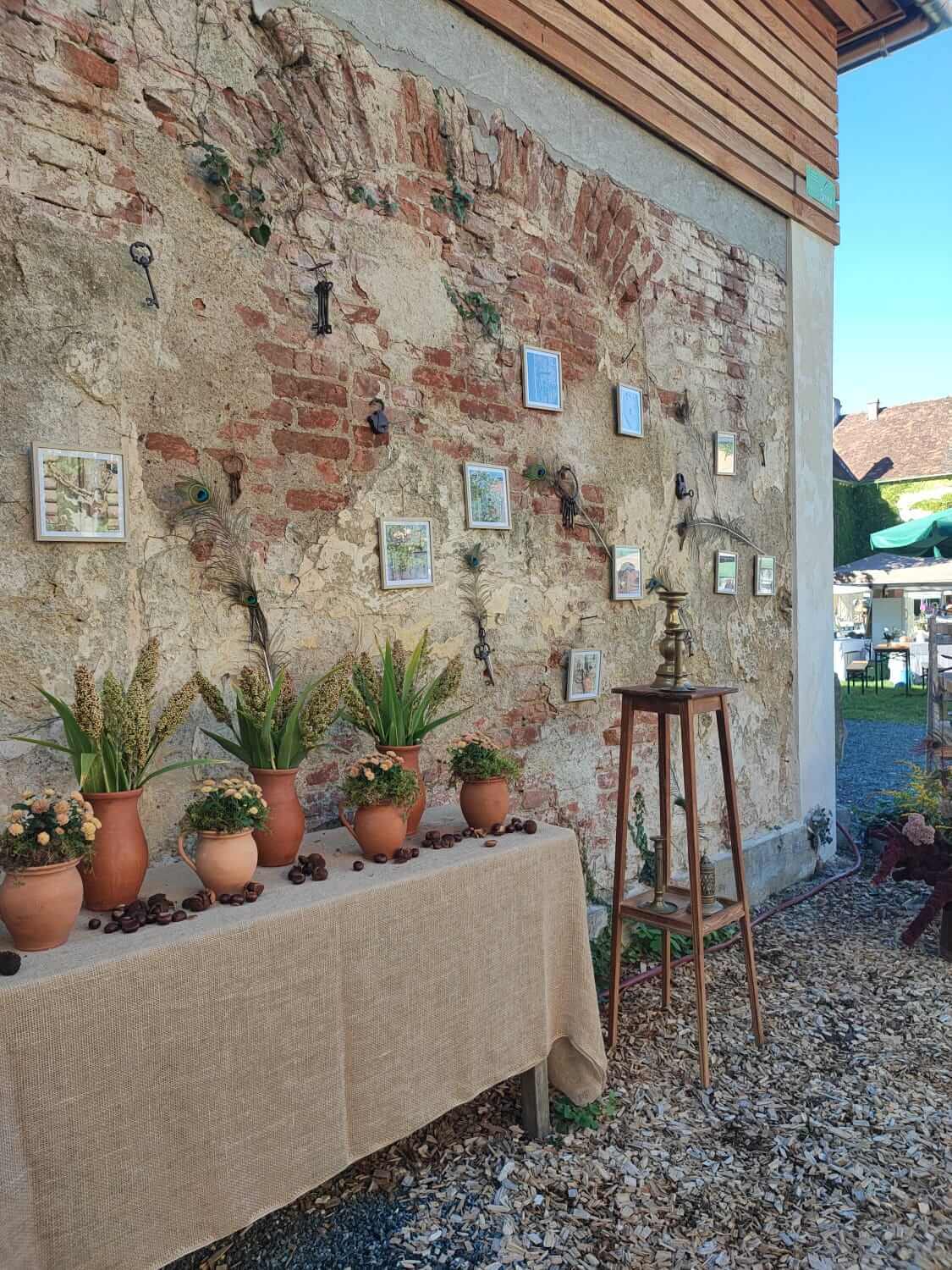 Rustikale Dekoration auf einem Hof mit Backsteinwand, Pflanzen in Tongefäßen und kunstvollen Wanddetails.