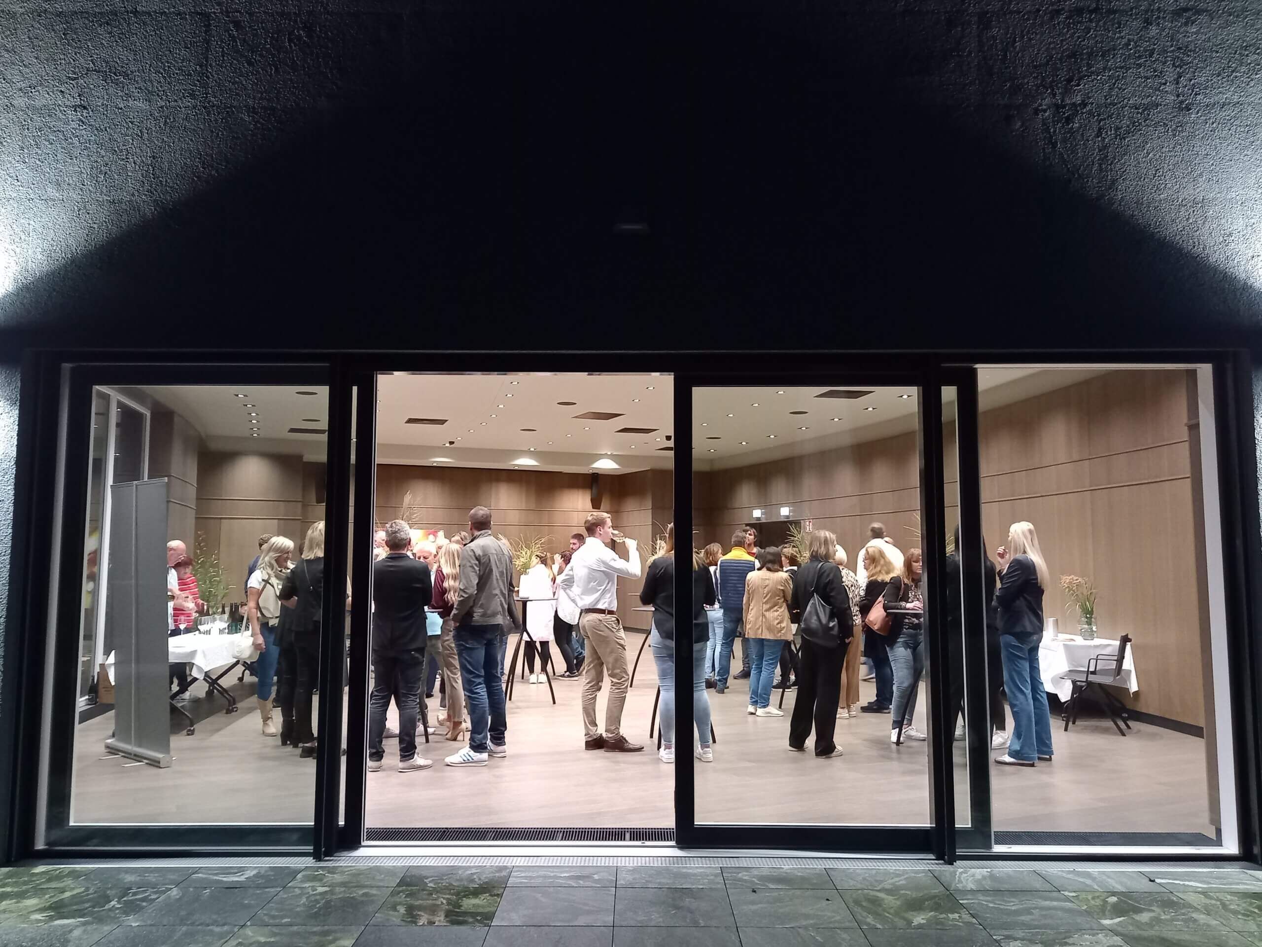 Gruppe von Menschen in einem modernen Konferenzraum bei Nacht, versammelt für eine Veranstaltung oder ein Treffen.