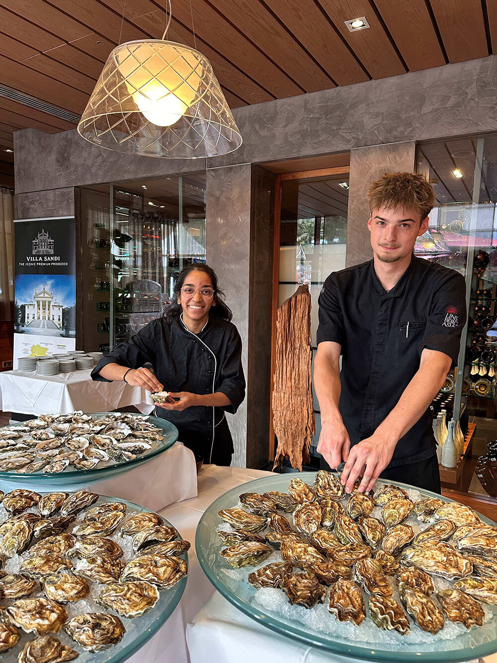 Köche servieren frische Austern auf Eisplatten in einem stilvollen Restaurant.