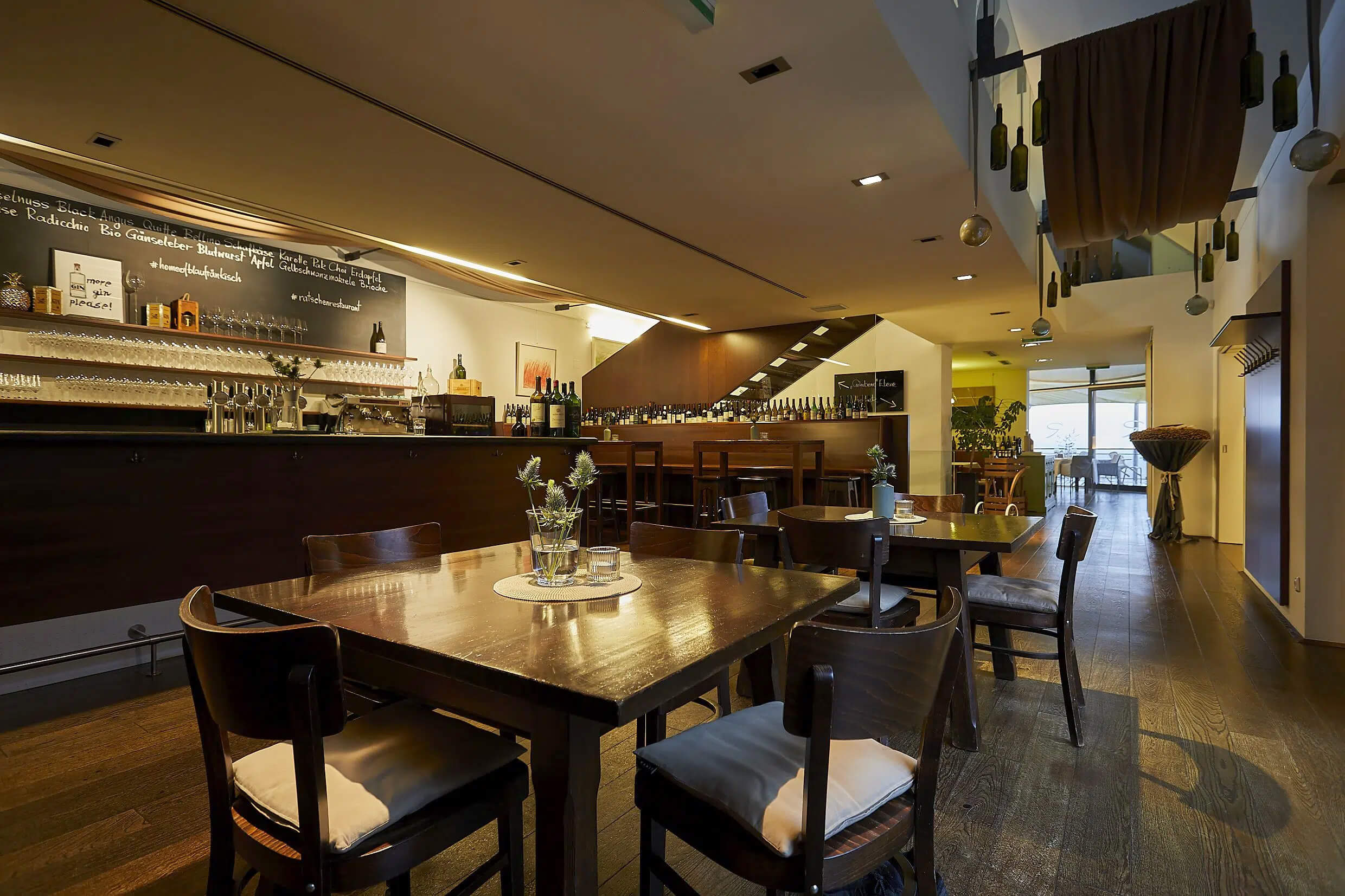 Moderner Restaurant-Innenraum mit Holztischen und Barbereich, einladend und stilvoll eingerichtet.