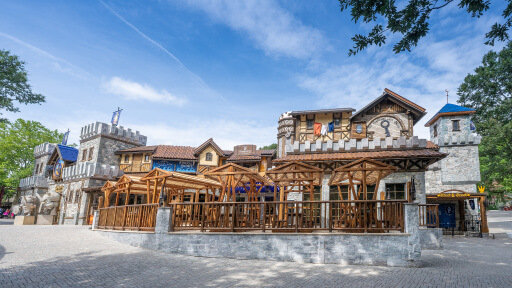 Mittelalterliches Gebäude mit Holzkonstruktionen und Türmen an einem sonnigen Tag im Freiluftpark.