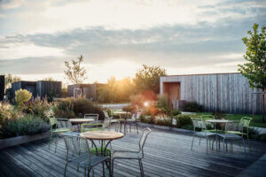 Sonnige Terrasse mit modernen Stühlen und Tischen, umgeben von natürlicher Landschaft, ideal für entspannte Freizeitmomente.