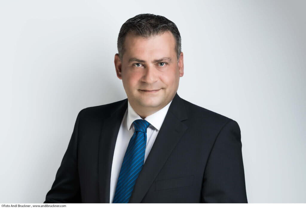 Ein Mann im Anzug mit blauer Krawatte blickt freundlich in die Kamera, ideal für ein regionales Magazinporträt.