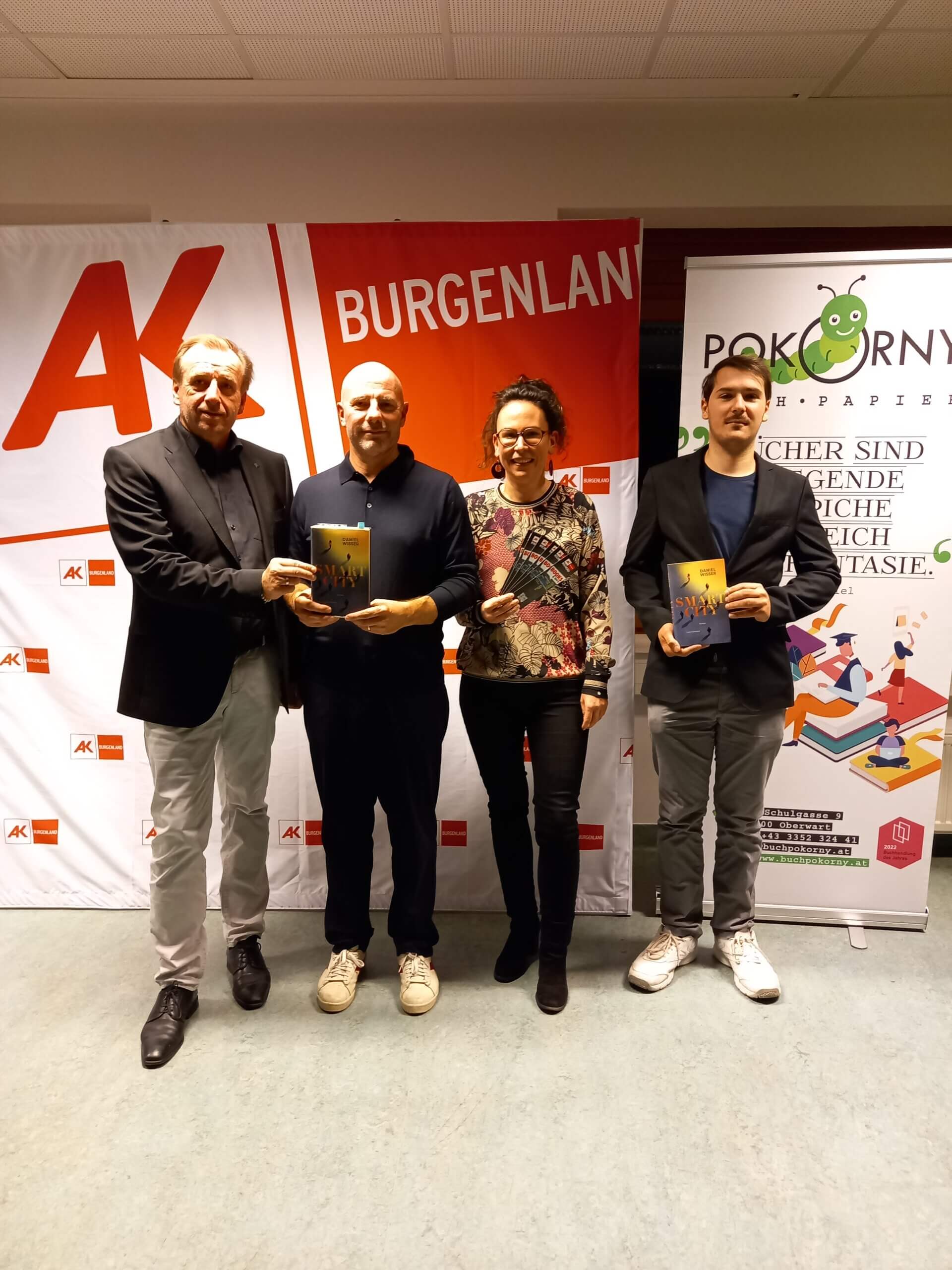 Vier Personen bei einer Buchvorstellung im Burgenland vor Bannern, die Bücher präsentieren.