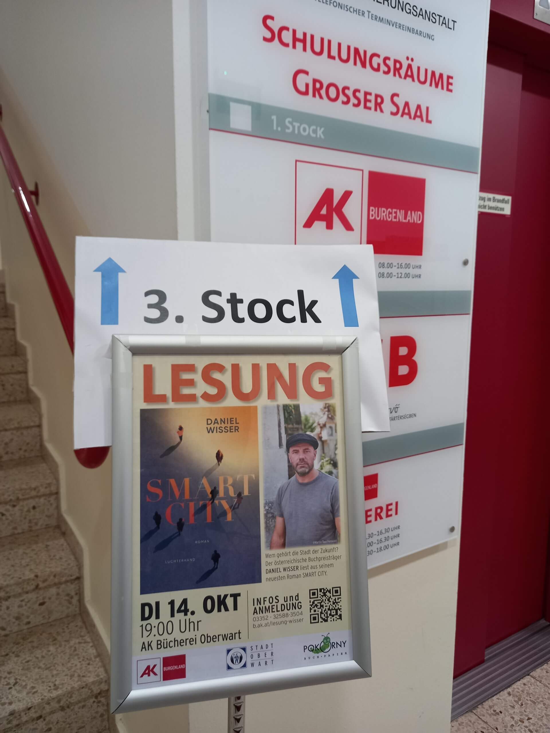 Lesung von Daniel Wisser aus Smart City am 14. Oktober, 19 Uhr in der AK Bücherei Oberwart, Hinweis im Treppenhaus.