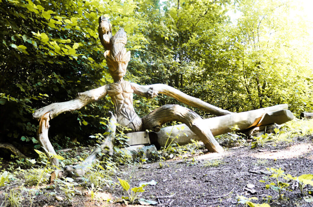 Bei 300jährigen Eiche Holzskulptur eines Baumwesens in einem grünen Wald, Kreativität und Natur vereint. Ideal für Prima Magazin.