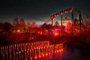 Achterbahn bei Nacht mit leuchtenden Lichtern und Wasserfontänen, festliches Ambiente, aufgenommen für Prima Magazin.