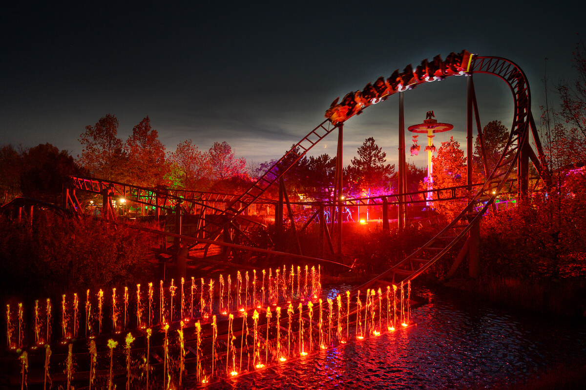 Achterbahn bei Nacht mit leuchtenden Lichtern und Wasserfontänen, festliches Ambiente, aufgenommen für Prima Magazin.