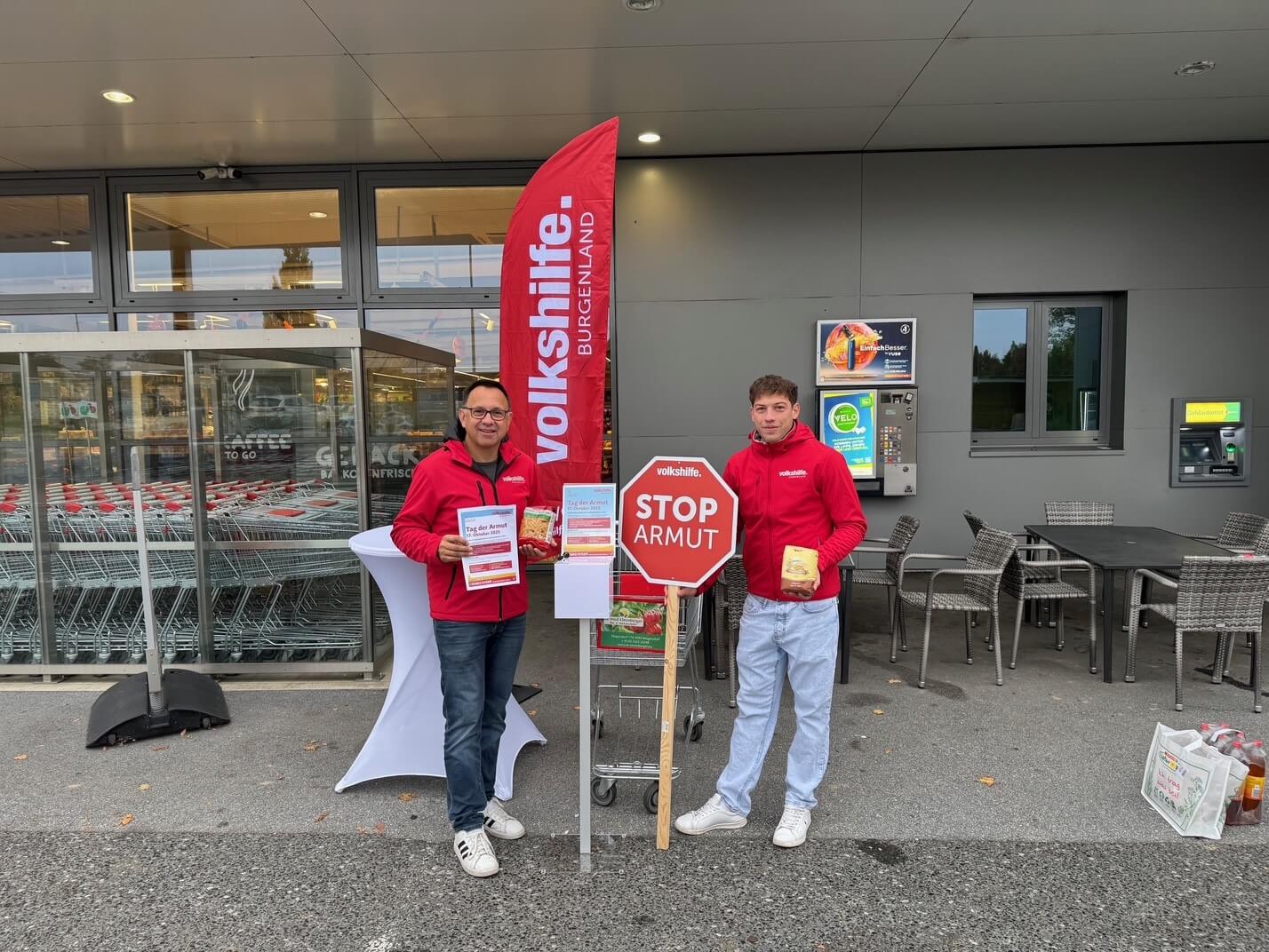 Freiwillige in Rot vor einem Supermarkt, werben für die Volkshilfe Burgenland und sammeln Spenden gegen Armut.