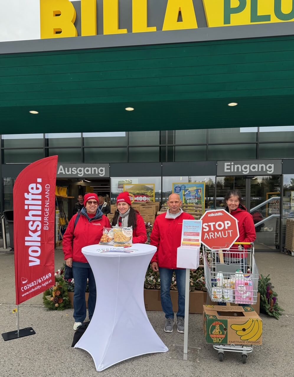 Gruppenausstellung vor einem Supermarkt mit Stop Armut-Schild, organisiert von der Volkshilfe Burgenland.