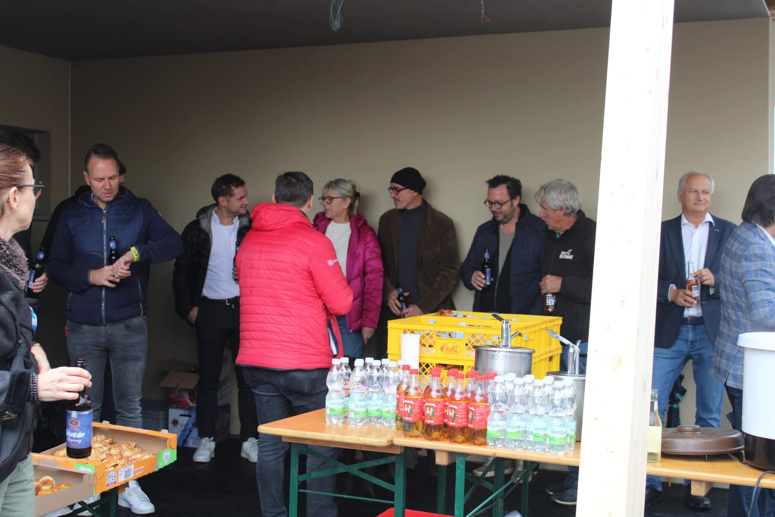 Personengruppe bei geselligem Treffen mit Getränken und Snacks in lockerer Atmosphäre, geeignet für regionales Magazin.