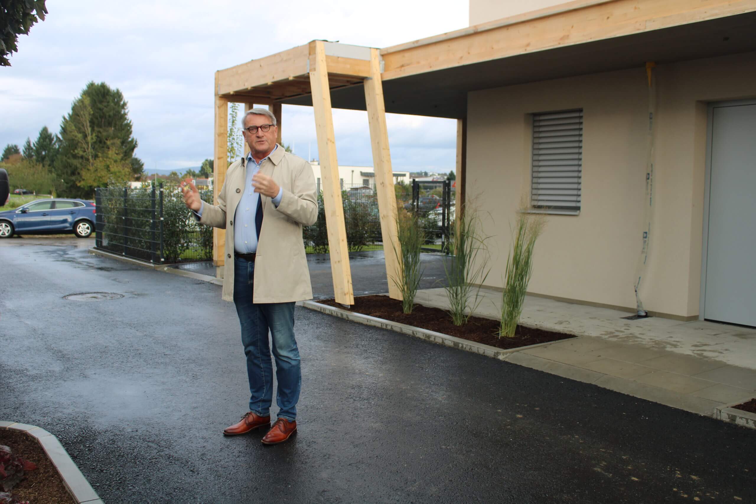 Mann steht vor einem modernen Gebäude, präsentiert ein Bauprojekt, ideal für regionales Magazin über lokale Entwicklungen.