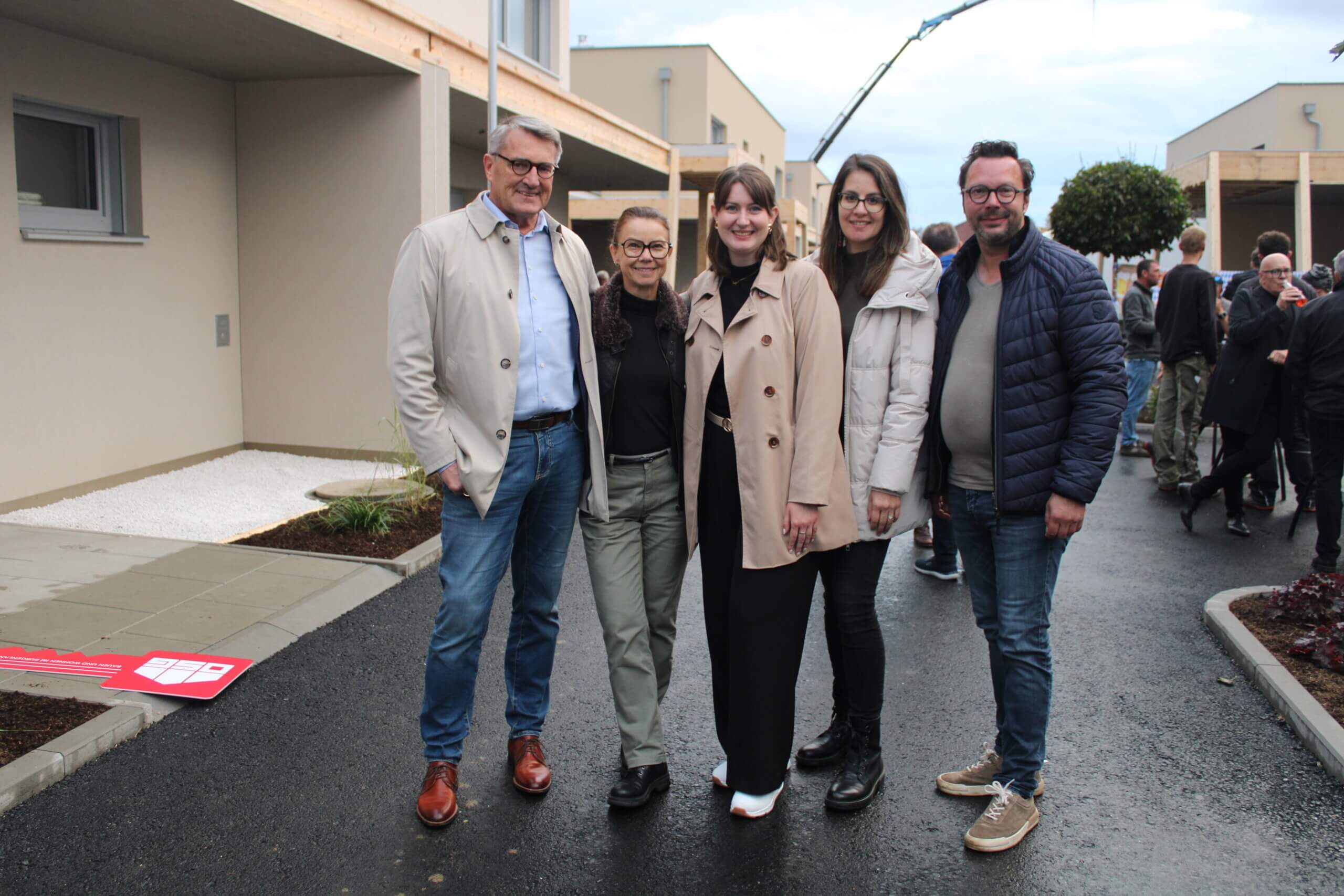 Gruppe von fünf Personen bei der Eröffnung eines modernen Gebäudes, lächelnd und in Freizeitkleidung, im Kontext eines Magazins.