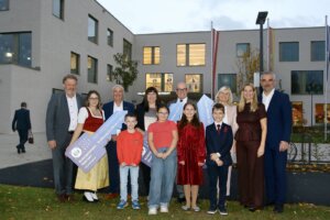 Eine Gruppe von Menschen steht lächelnd vor einem modernen Gebäude bei der Eröffnung des Bildungscampus Oberwart.