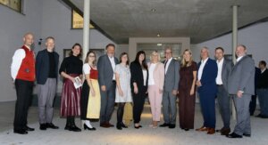 Gruppe von Personen in festlicher Kleidung posiert lächelnd in einem modernen Gebäude für ein regionales Magazin-Shooting.