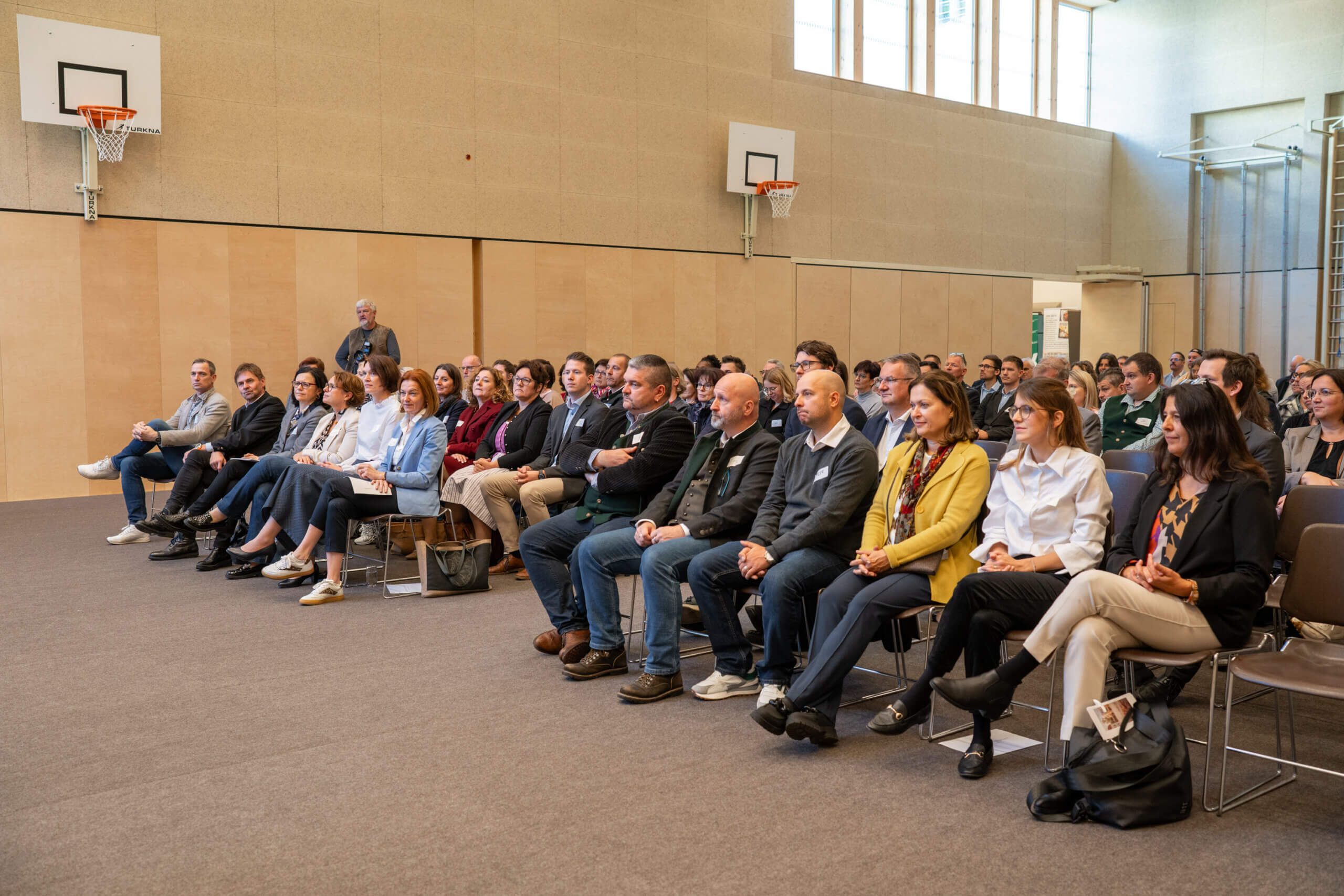 Teilnehmer hören in einer Sporthalle aufmerksam einem Vortrag zu, im Rahmen einer Veranstaltung von Prima Magazin.