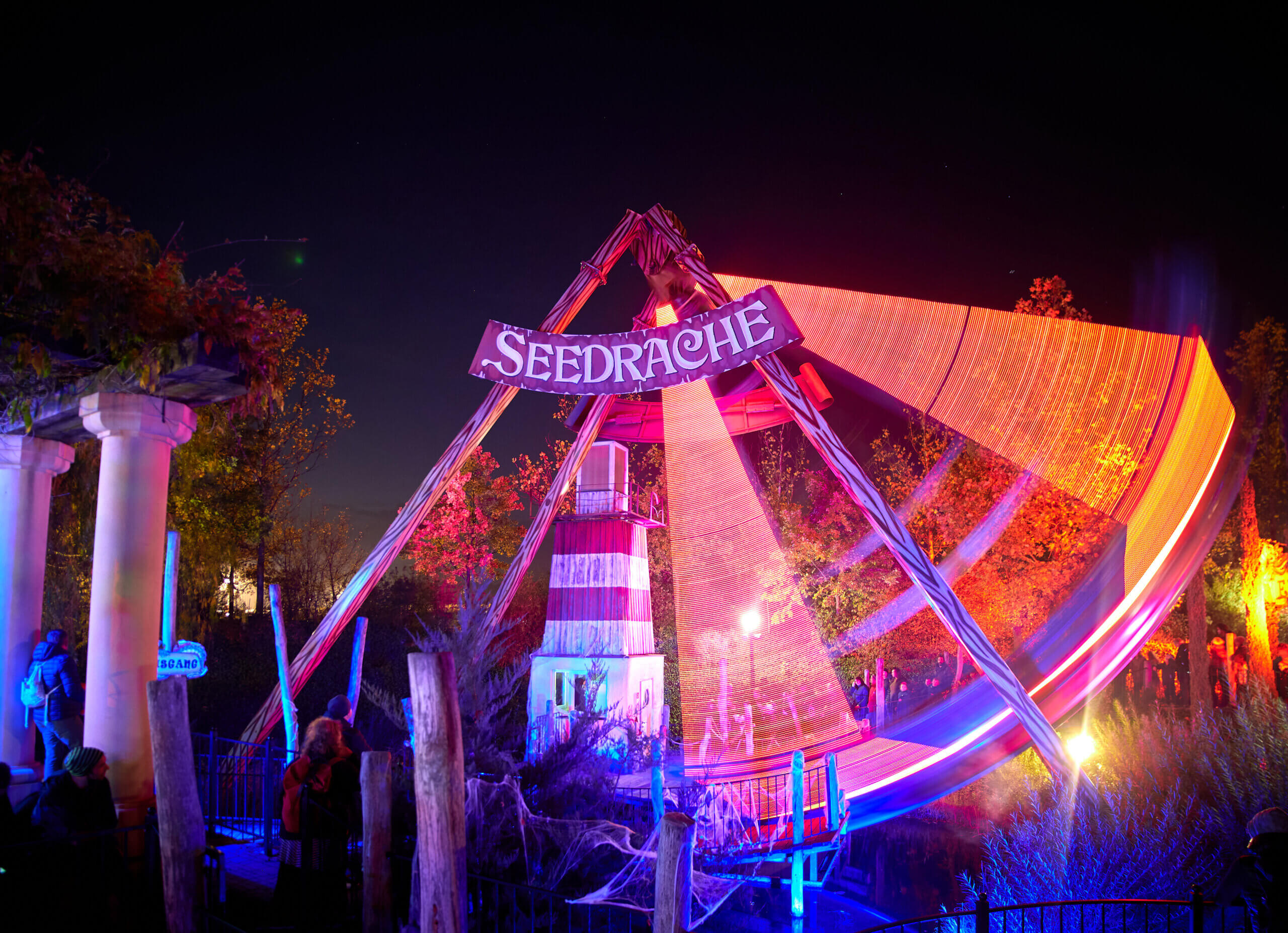 Lichtershow im Freizeitpark: Leuchtende Seesägen-Attraktion bei Nacht zieht begeisterte Besucher im Park an.