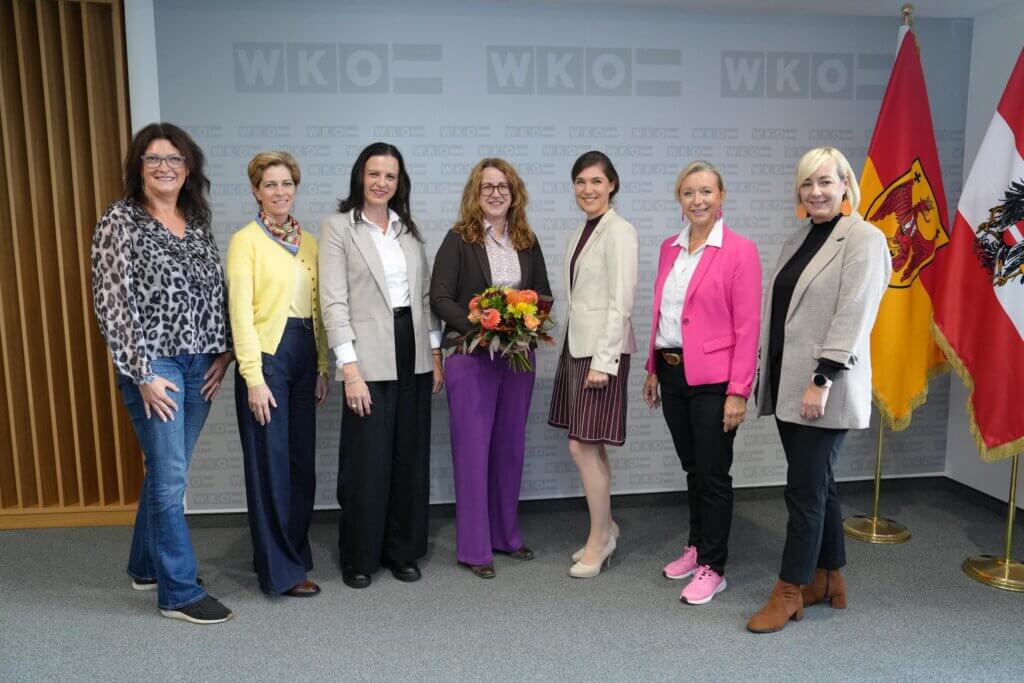 frau-in-der-wirtschaft Eine Gruppe von sieben Frauen posiert bei einem Event der Wirtschaftskammer, eine hält einen Blumenstrauß.