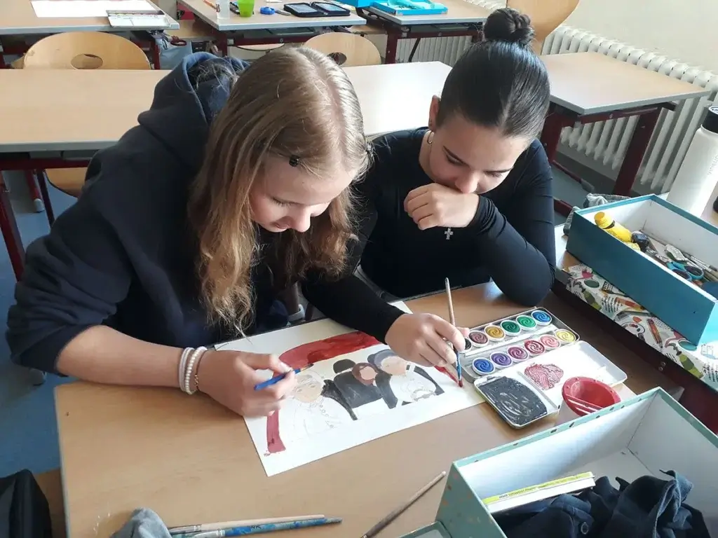 Zwei Schülerinnen malen gemeinsam ein Bild mit Wasserfarben im Kunstunterricht, gefördert von regionalem Bildungsprogramm.