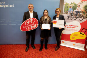 Drei Personen präsentieren bei einer Veranstaltung Burgenland radelt Schilder; regionale Initiative im Burgenland für Radfahrer.