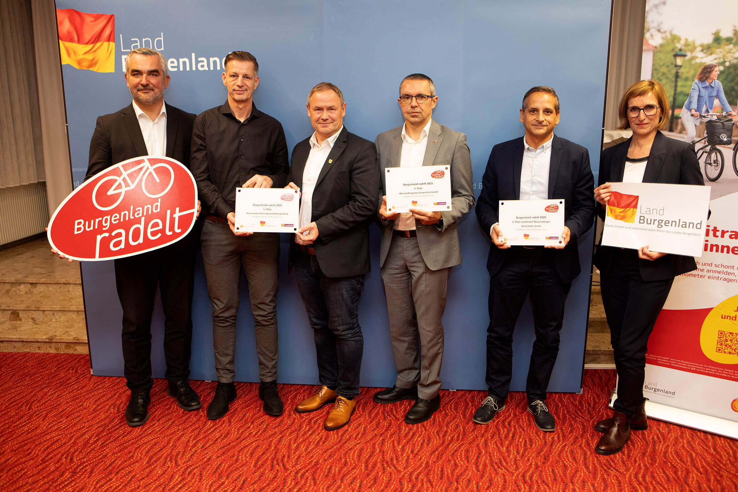 Gruppe von sieben Personen präsentiert Burgenland radelt Schilder und Urkunden bei einer Veranstaltung im Burgenland.