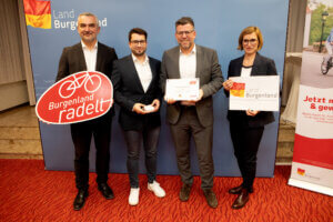 Vier Personen präsentieren bei einem Event des Landes Burgenland die Initiative Burgenland radelt mit Schildern und Urkunde.