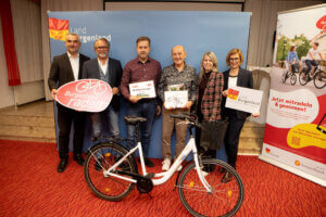 Gruppe bei Burgenland radelt Event mit Fahrrad und Plakaten, fördert Radfahren als umweltfreundliche Initiative.