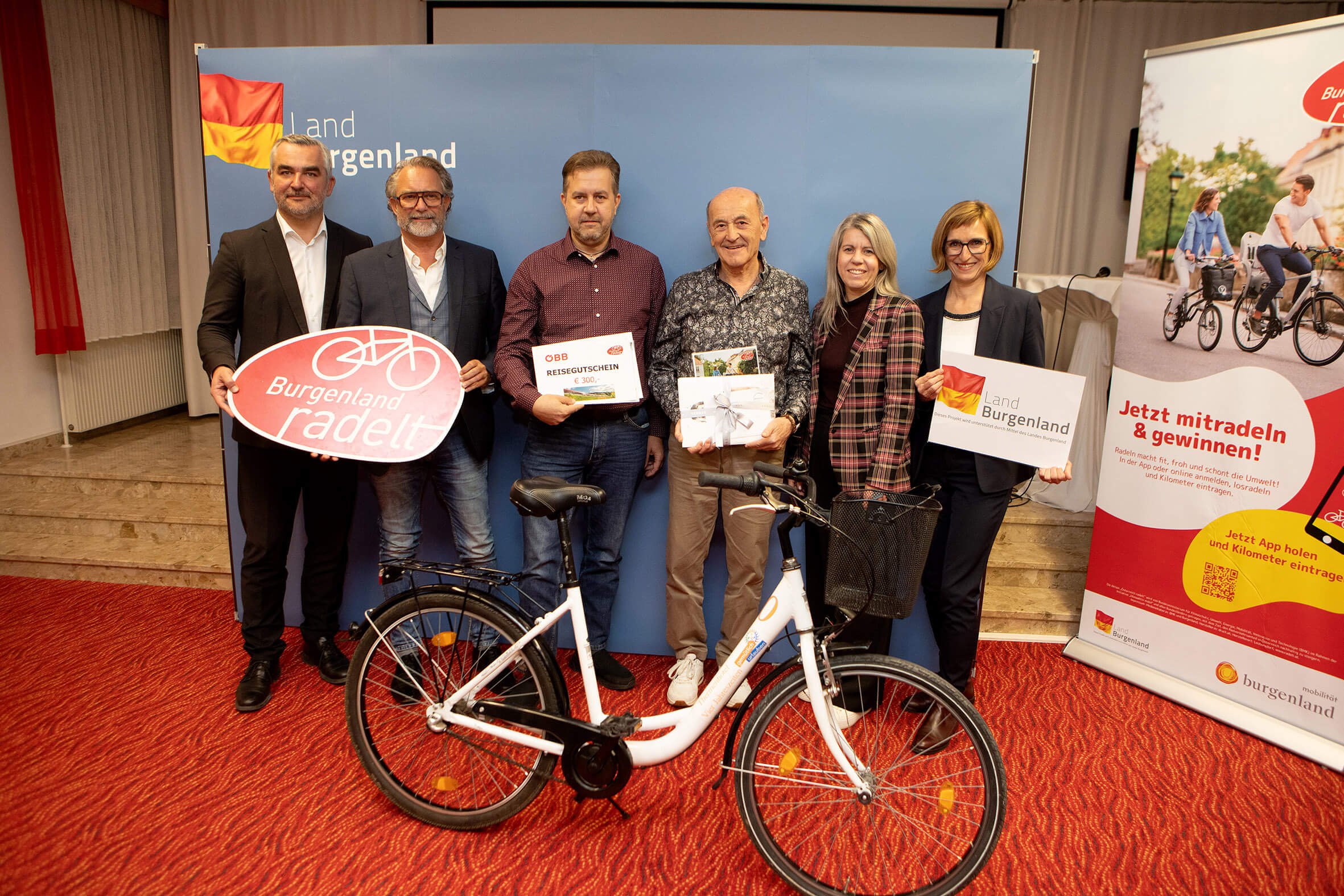 Gruppe bei Burgenland radelt Event mit Fahrrad und Plakaten, fördert Radfahren als umweltfreundliche Initiative.