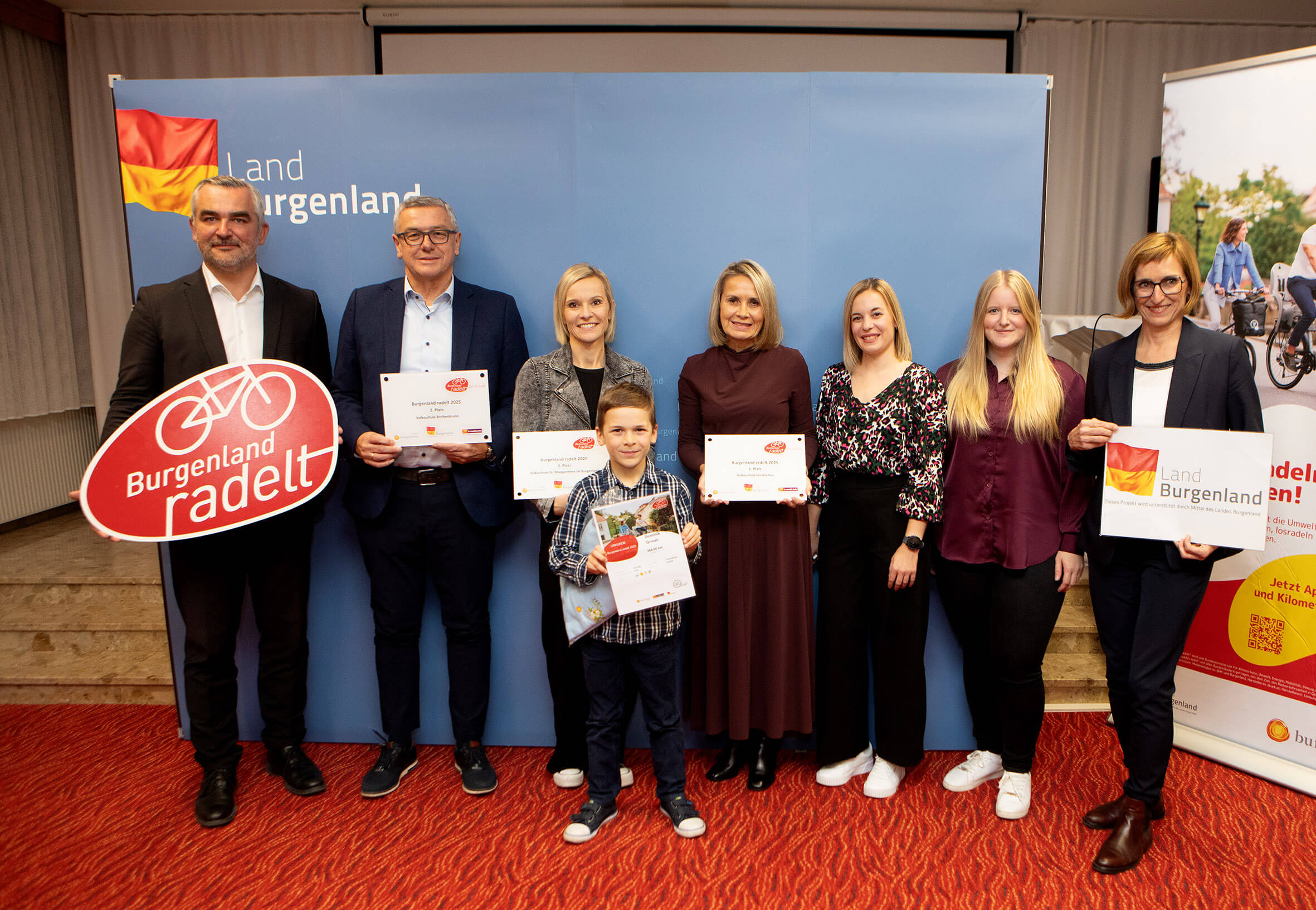 Eine Gruppe hält Auszeichnungen bei der Burgenland radelt-Veranstaltung, unterstützt vom Land Burgenland.