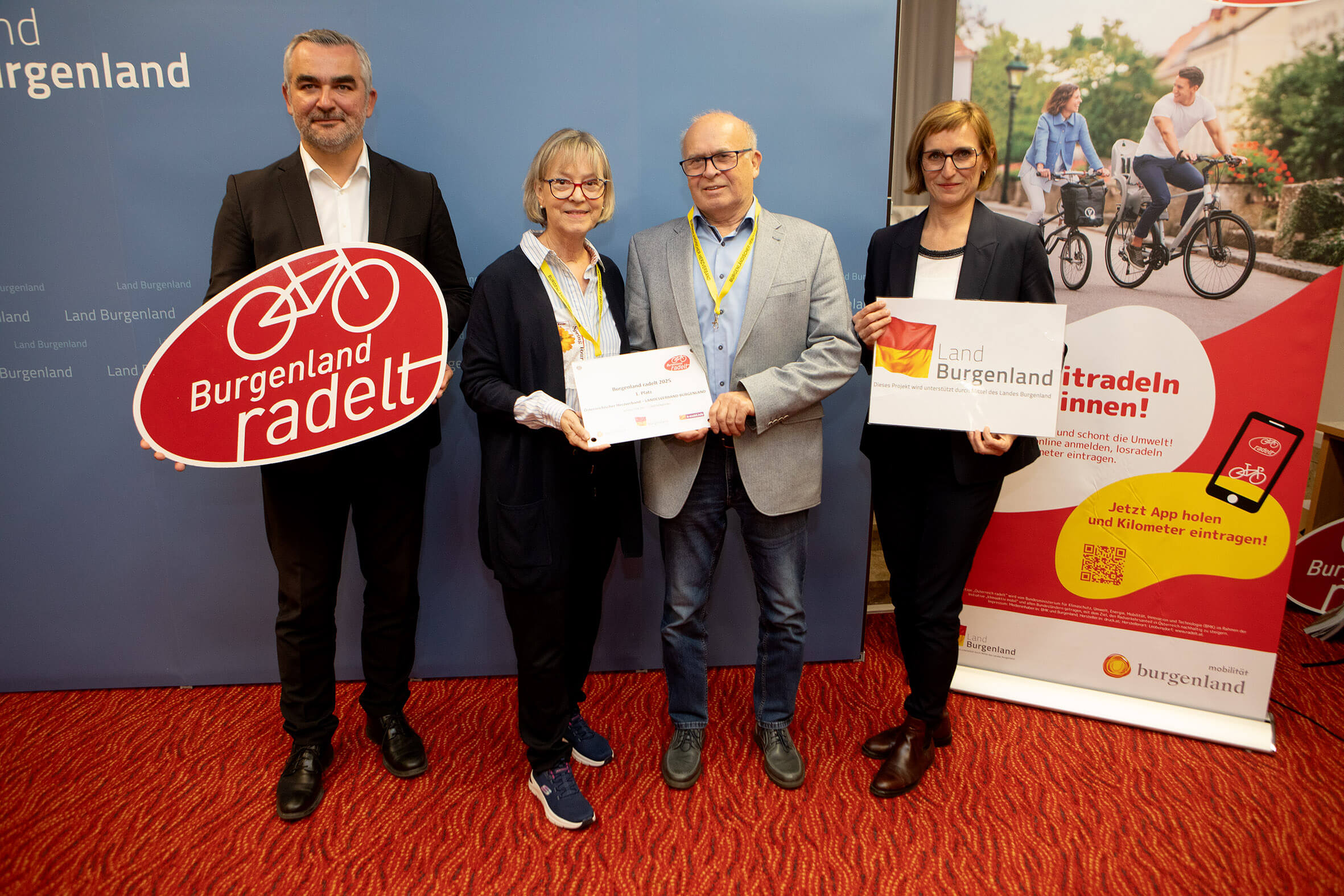 Vier Personen präsentieren Auszeichnungen für die Initiative „Burgenland radelt“ von Land Burgenland auf rotem Teppich.