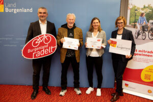 Preisverleihung von Burgenland radelt mit vier Personen, die Urkunden und Schilder halten. Thema: regionale Mobilität.