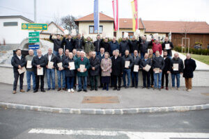 Gruppe von Menschen mit Auszeichnungen vor einem regionalen Gebäude, symbolisiert Gemeinschaft und lokale Anerkennung im Prima Magazin.