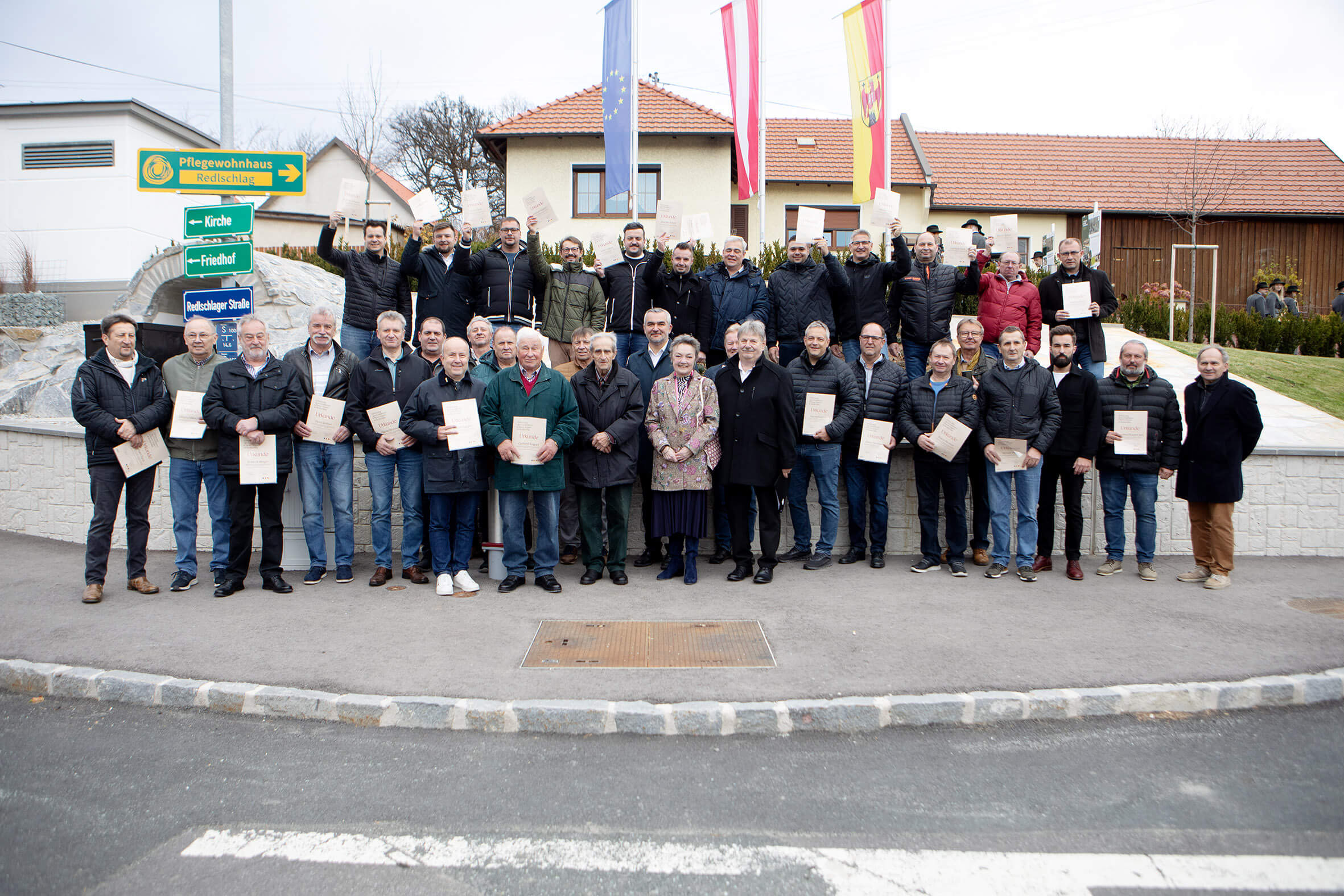 Gruppe von Menschen mit Auszeichnungen vor einem regionalen Gebäude, symbolisiert Gemeinschaft und lokale Anerkennung im Prima Magazin.