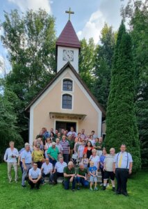 Gruppe von Menschen versammelt vor der Halper-Kapelle in ländlicher Umgebung, festliches Treffen bei Prima Magazin.