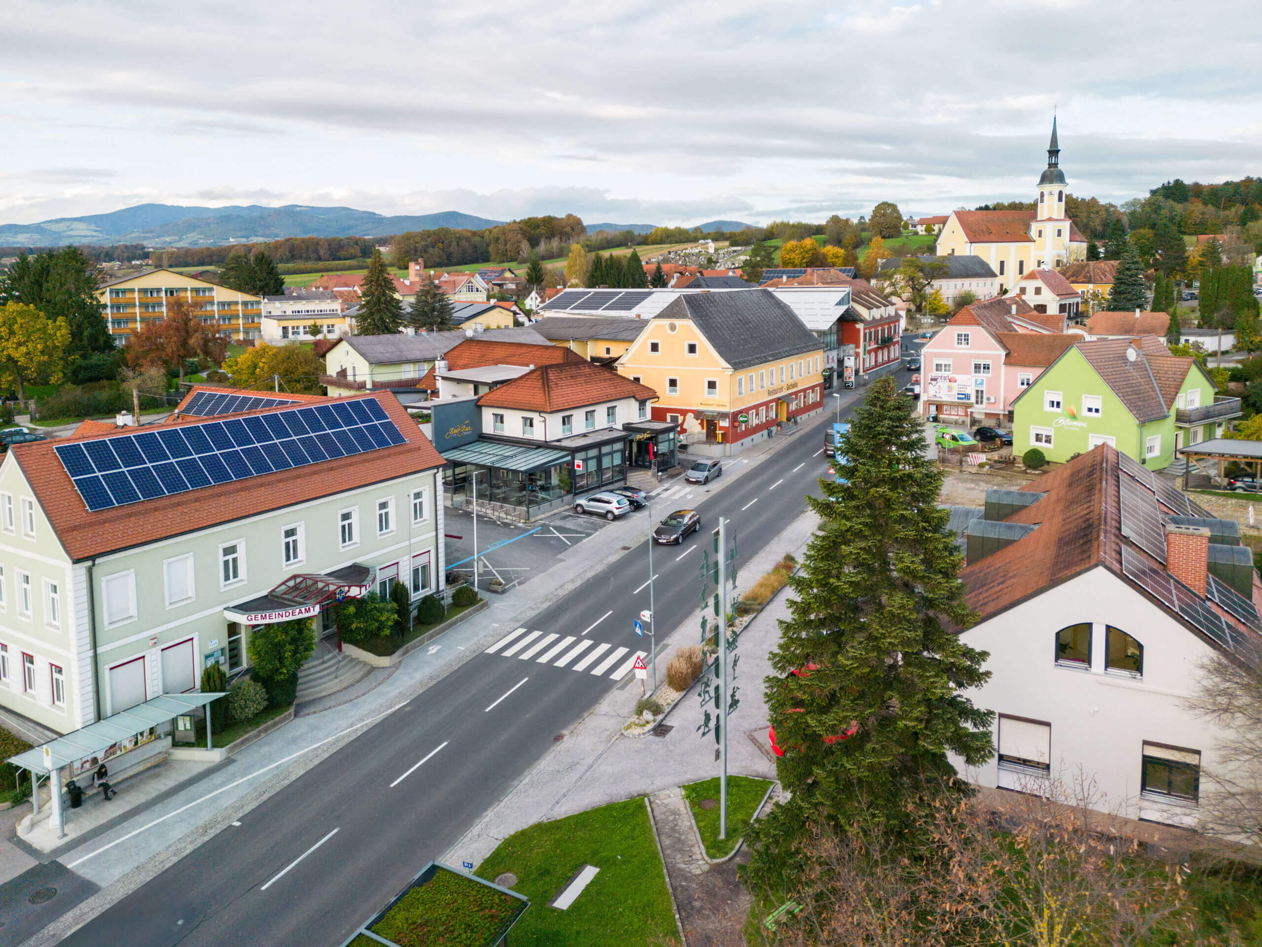 Kleinstadtpanorama mit Kirche, Hauptstraße und Gebäuden unter Solarzellen, ideal für regionales Magazin über nachhaltige Entwicklung.
