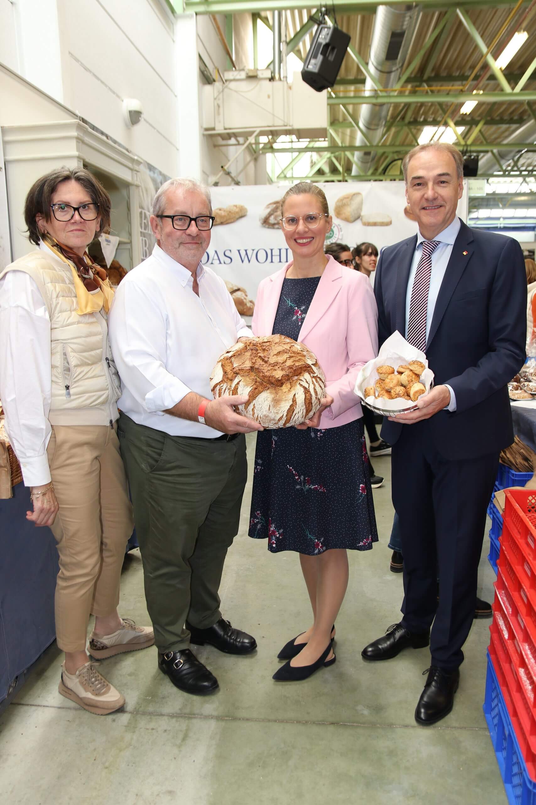 Gruppe präsentiert regionales Brot und Gebäck auf Messe, symbolisiert Engagement für lokale Backkunst und Qualitätsjournalismus.